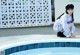 A woman crouching on the edge of a swimming pool.