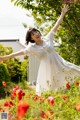 A woman in a white dress standing in a field of red flowers.