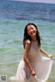 A woman in a white dress standing in the water.