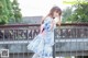 A young woman in a blue and pink dress standing on a bridge.