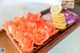 A tray of orange roses and lemons on a table.