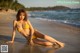 A woman in a yellow bikini sitting on the beach.