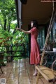 A woman in a red dress standing on a porch.