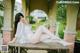 A woman in a white lingerie sitting on a wooden table.