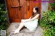 A woman sitting on the ground in front of a wooden door.