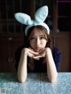 A woman wearing a bunny ears headband sitting at a table.