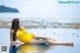 A woman in a yellow bathing suit sitting in the water.