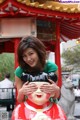 A woman covering her eyes with her hands in front of a statue.